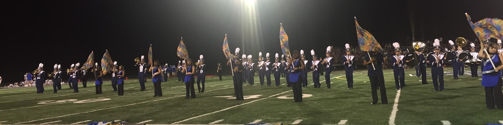 Addison Trail marching band and color guard performing on the football field
